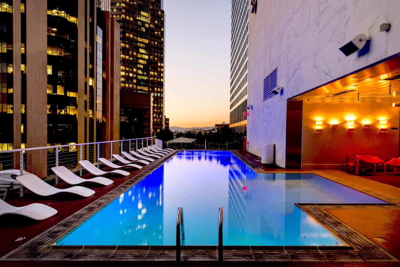 heros-img Elegant rooftop pool with cityscape backdrop at sunset, reflecting urban luxury.